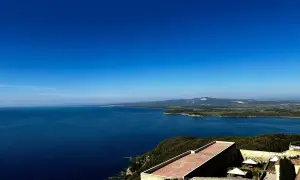 Vista panoramica sul mare blu intenso della Maremma, con colline verdi e un borgo antico. Perfetto per scoprire cosa vedere in Maremma.