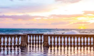 Tramonto sulla Terrazza Mascagni a Livorno, con onde che si infrangono e cielo colorato.