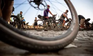 Ciclisti pronti per nuovi itinerari in bici, con le ruote in primo piano che promettono avventura su strade acciottolate.