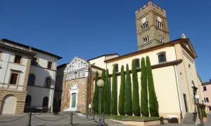 Piazza ad Altopascio dove si trova la chiesa con campanile medievale e cipressi slanciati.