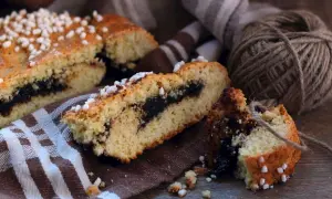 Fette di dolci emiliani con ripieno scuro, guarnite con zuccherini, su un tovagliolo a righe.