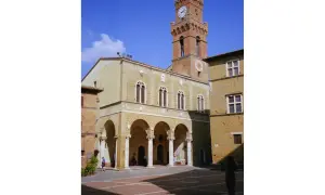 Il **Palazzo Comunale di Pienza** domina la piazza con la sua torre dell'orologio. Archi eleganti e finestre gotiche caratterizzano l'edificio.