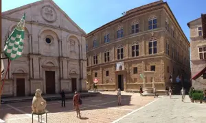 La **Pienza piazza** è un luogo incantevole con un duomo imponente e palazzi rinascimentali. Una scultura e bandiere colorate aggiungono vivacità.