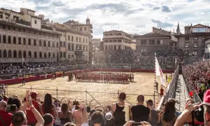Un campo di sabbia a Firenze, gremito di spettatori, ospita un'intensa partita di calcio storico.