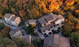 Borgo autunnale a Montale PT, Italia, con case in pietra e tetti in cotto immerse nel foliage colorato.