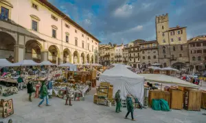 Mercato all'aperto a San Gimignano, con bancarelle di antiquariato e artigianato sotto un cielo nuvoloso.