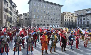 Sfilata storica a San Giovanni, Firenze. Uomini in costume rinascimentale, con armature e bandiere, celebrano la festa.