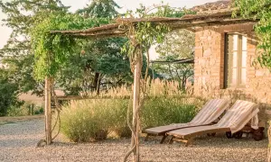 Due lettini prendisole sotto un pergolato fiorito, con vista sui borghi vicino Radicofani.