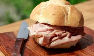 Panino con mortadella su tagliere di legno, un'ottima idea per sapere dove fermarsi tra Bologna e Firenze.