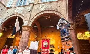 Sfilata storica a Siena con stendardi e costumi d'epoca, evocando l'atmosfera del Palio.