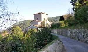 Strada panoramica verso Sant'Andrea di Compito, con un antico borgo in pietra e vegetazione rigogliosa.