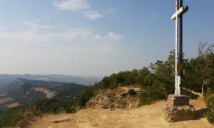 Croce in cima a un crinale roccioso, con un panorama mozzafiato sulle montagne dell'Emilia Romagna.