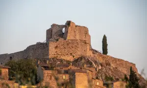 Rocca Aldobrandesca a Castiglione d'Orcia, un antico maniero in pietra che domina il borgo, con un cipresso solitario a vegliare.