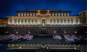 Il mercato di Livorno illuminato di notte, con barche ormeggiate e il loro riflesso sull'acqua.