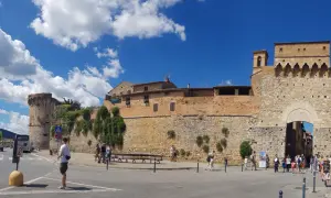 La **Siena Fortezza Medicea** domina il paesaggio con le sue mura imponenti. Turisti passeggiano sotto il sole, ammirando la storia.