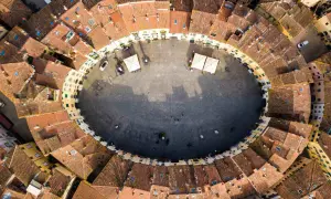 Vista aerea della **Piazza Anfiteatro** di Lucca, con i suoi caratteristici edifici ovali e i tetti rossi che la circondano.