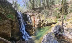 Cascata nel bosco, acque cristalline del fiume Merse che scendono tra rocce e vegetazione lussureggiante.