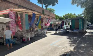 Mercato all'aperto a Grosseto, con bancarelle colorate di tessuti e abbigliamento sotto un cielo azzurro.