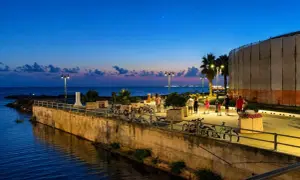Passeggiata serale lungo il mare a Follonica, con persone che camminano e biciclette parcheggiate.