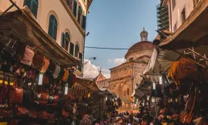 Mercato fiorentino con borse in pelle e cupole sullo sfondo, un assaggio della firenze non turistica.