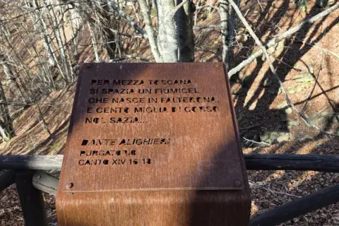 Targa arrugginita sul monte Falterona con citazione di Dante Alighieri sul fiume che nasce qui.
