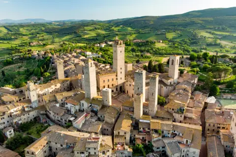 San Gimignano, con le sue torri medievali che svettano tra i tetti, incanta in un paesaggio collinare toscano.