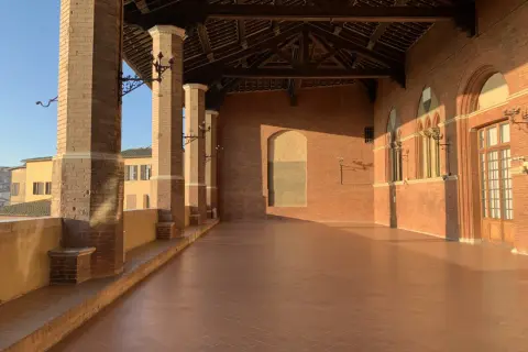 La loggia dei Nove a Siena, con le sue colonne in cotto e il tetto a capriate, baciata dalla luce dorata del tramonto.
