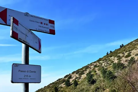 Segnaletica escursionistica sul **Monte Pisano**, indica il Passo di Dante a 215 m e sentieri per S. Giuliano Terme.