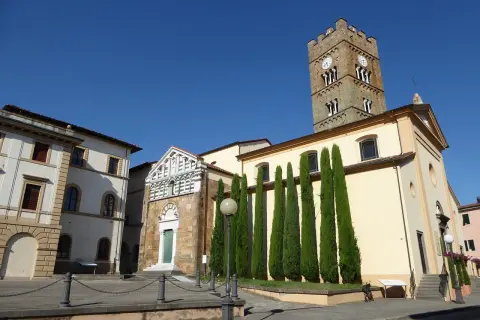 Piazza ad Altopascio dove si trova la chiesa con campanile medievale e cipressi slanciati.