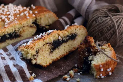 Fette di dolci emiliani con ripieno scuro, guarnite con zuccherini, su un tovagliolo a righe.