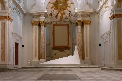Installazione moderna in un ambiente storico, tra i musei di Livorno. Una scultura bianca a forma di onda domina la scena.