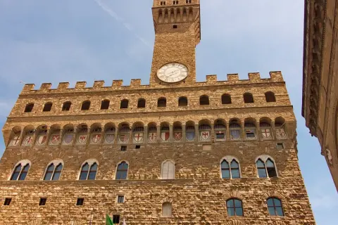 Palazzo Vecchio, simbolo di Firenze medievale, con la sua torre imponente e gli stemmi araldici.