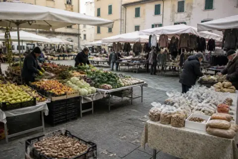 Mercato all'aperto a Marina di Massa con bancarelle di frutta, verdura e abbigliamento.