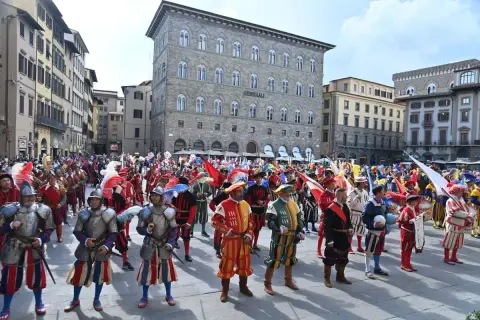 Sfilata storica a San Giovanni, Firenze. Uomini in costume rinascimentale, con armature e bandiere, celebrano la festa.
