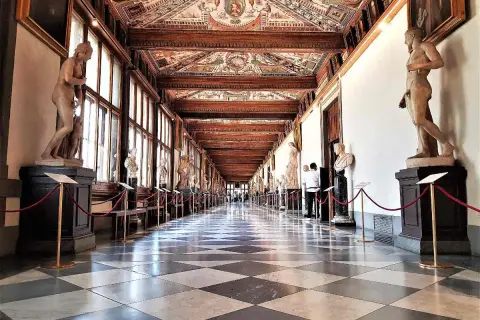Corridoio degli Uffizi con statue classiche e soffitto affrescato. Un assaggio di cosa vedere agli Uffizi, tra capolavori e architettura.