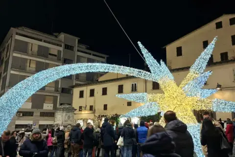 Luci natalizie scintillanti illuminano il poggibonsi markt, creando un'atmosfera magica tra la folla.