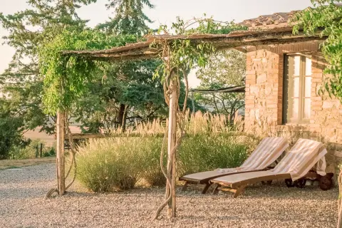 Due lettini prendisole sotto un pergolato fiorito, con vista sui borghi vicino Radicofani.