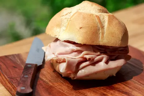Panino con mortadella su tagliere di legno, un'ottima idea per sapere dove fermarsi tra Bologna e Firenze.