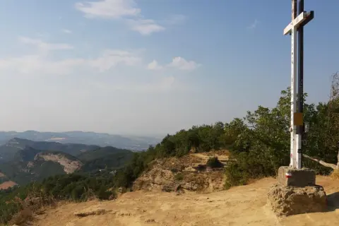 Croce in cima a un crinale roccioso, con un panorama mozzafiato sulle montagne dell'Emilia Romagna.