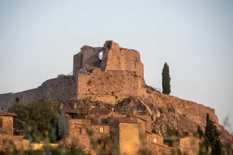 Rocca Aldobrandesca a Castiglione d'Orcia, un antico maniero in pietra che domina il borgo, con un cipresso solitario a vegliare.