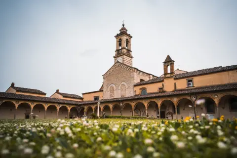 Cortile con portico ad archi e campanile, immerso in un prato fiorito. Un luogo sereno sul monte Senario.
