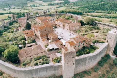 Vista aerea di Monteriggioni, un borgo medievale fortificato. Perfetto per scoprire cosa vedere a Monteriggioni, tra torri e mura imponenti.
