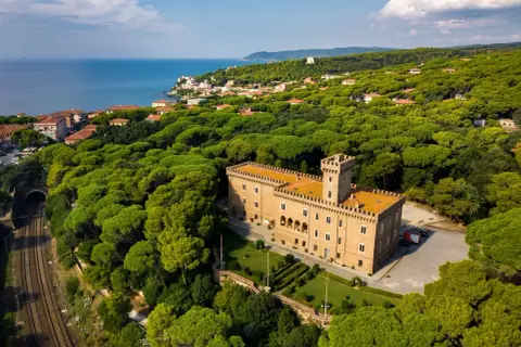 Castiglioncello cosa vedere: un castello imponente circondato da una pineta rigogliosa, con il mare all'orizzonte.