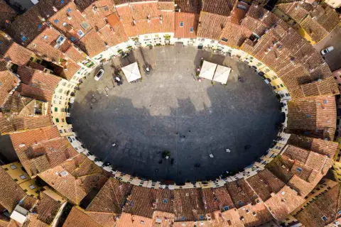 Vista aerea della **Piazza Anfiteatro** di Lucca, con i suoi caratteristici edifici ovali e i tetti rossi che la circondano.