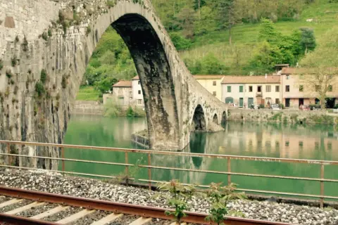 Ponte del Diavolo a Borgo a Mozzano, con case colorate e il fiume Serchio.
