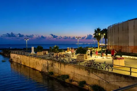 Passeggiata serale lungo il mare a Follonica, con persone che camminano e biciclette parcheggiate.