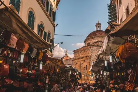 Mercato fiorentino con borse in pelle e cupole sullo sfondo, un assaggio della firenze non turistica.