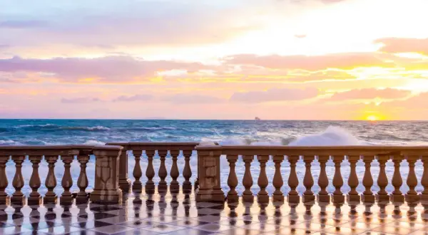 Tramonto sulla Terrazza Mascagni a Livorno, con onde che si infrangono e cielo colorato.