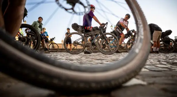 Ciclisti pronti per nuovi itinerari in bici, con le ruote in primo piano che promettono avventura su strade acciottolate.