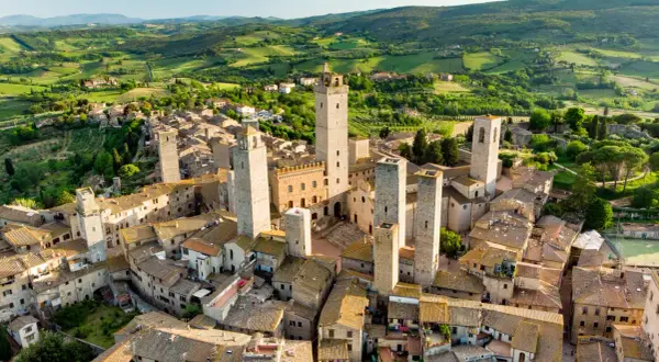 San Gimignano, con le sue torri medievali che svettano tra i tetti, incanta in un paesaggio collinare toscano.